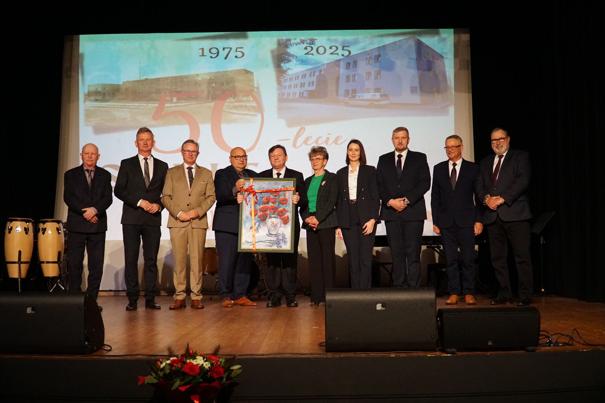 Zdjęcie przedstawia grupę osób stojących na scenie w kinie Świt podczas Jubileuszu 50-lecia szpitala w Zwoleniu
