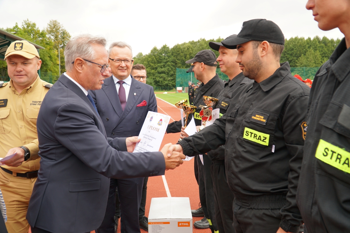 Zdjęcie przedstawia starostę zwoleńskiego, kt&oacute;ry wręcza nagrodę strażakom